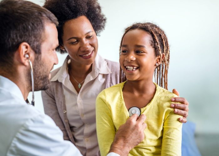 Healthcare medical exam people children and medicine concept. Close up of happy girl and doctor with stethoscope listening to heartbeat