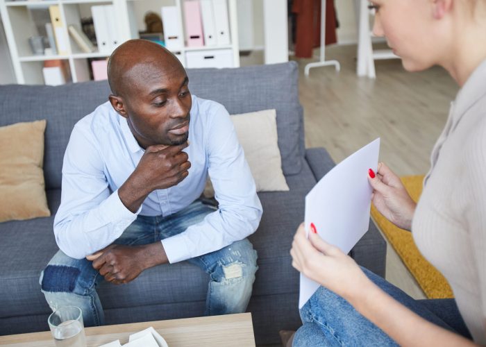 Female psychoanalyst showing pictures to pensive Black patient and asking to describe what he sees at therapy session